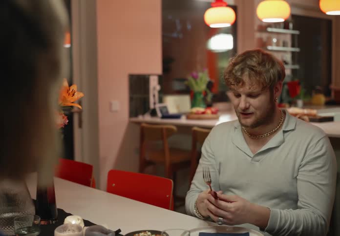 One man discusses the utensils while sitting at table with woman at night