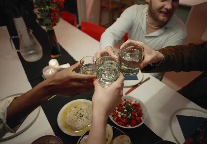 Four friends sitting at the dinner table having dinner toasting before eating