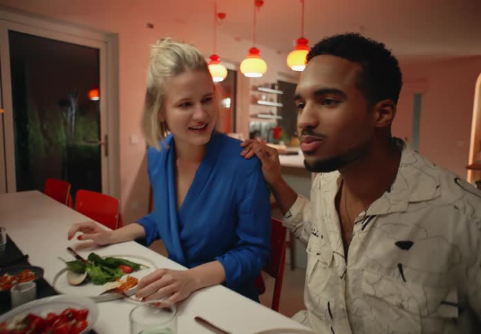 Gay and straight couples sitting at table have dinner and talk to each other laughing in room