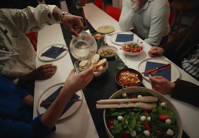 Gay and straight couples eat dinner sitting at dining table