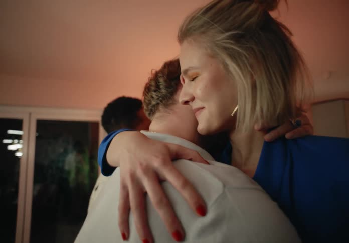 Straight and gay couples greet and hug each other in room smiling