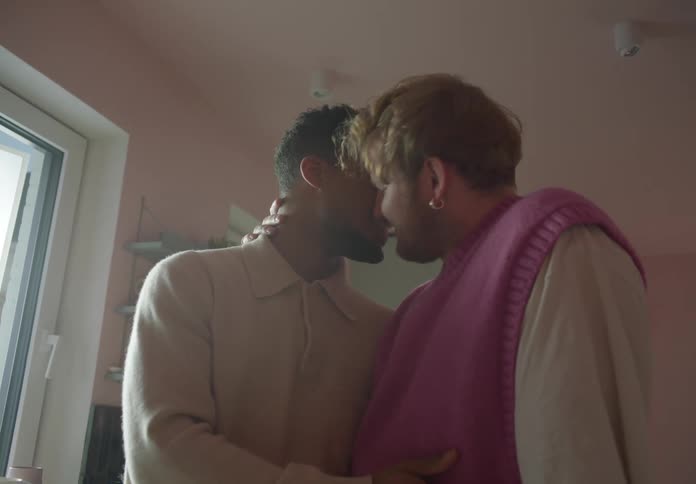 Couple cuddles and smiles at home near kitchen shelves