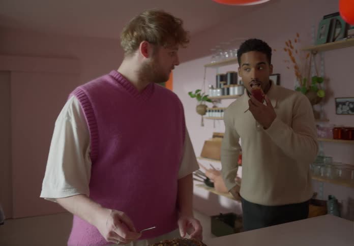 A man cuddles up to his boyfriend in the kitchen then steals the toast