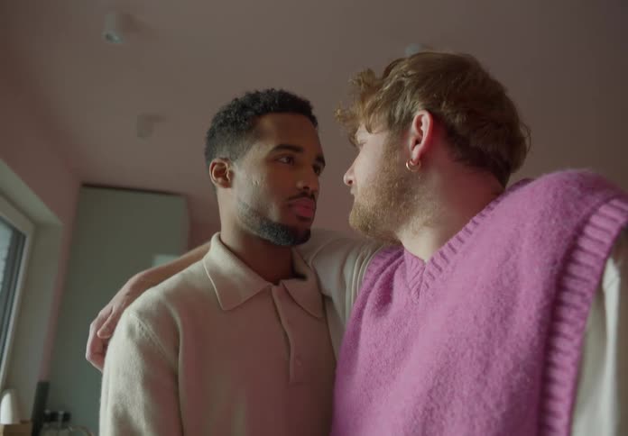 A man has his arm around his boyfriend as they look into each others eyes and smile
