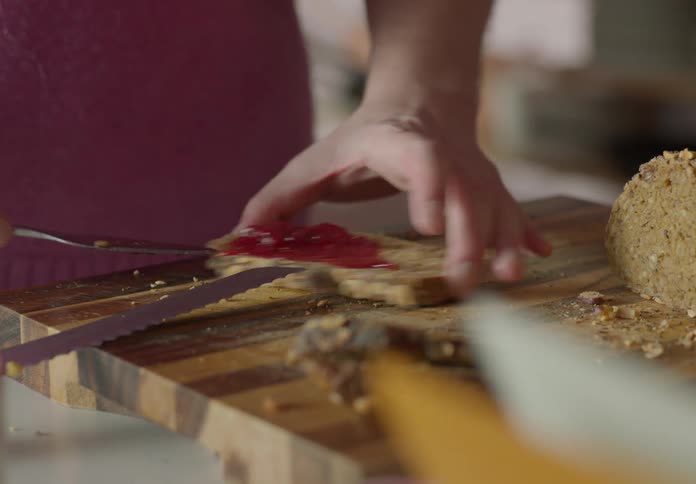 A man at home spreads jam on a piece of bread