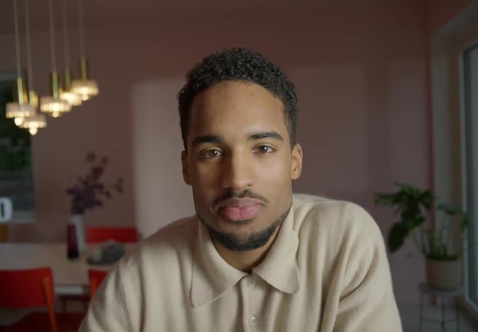 Man with beige sweatshirt smiles at camera