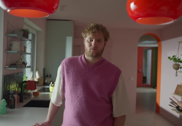 A man standing in his kitchen with his hand on the counter looking sad