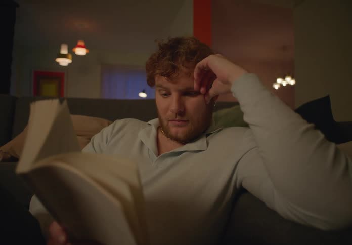 A man reads a book while sitting on a couch indoors