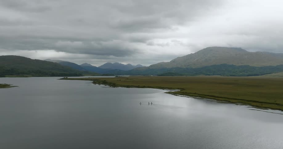 A view of a lake with mountains in the distance with paddleboarders