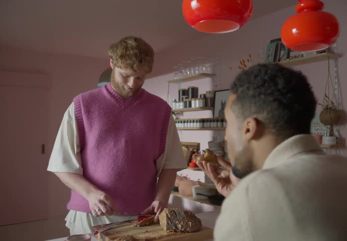 Gay couple spreads jam on bread and eats it in the kitchen