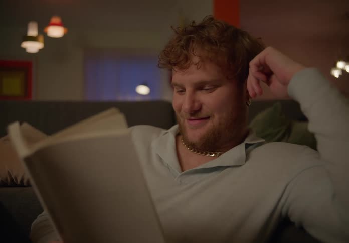 Man sitting on the sofa in the living room smiling while reading a book