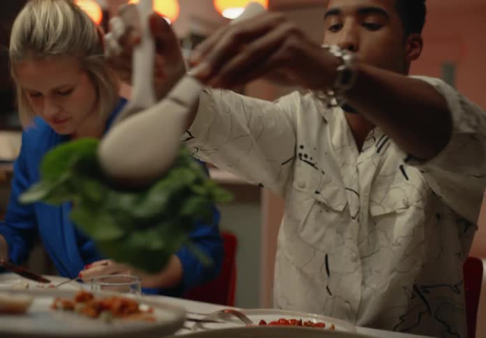 Man serves salad at dinner with friends with a smile