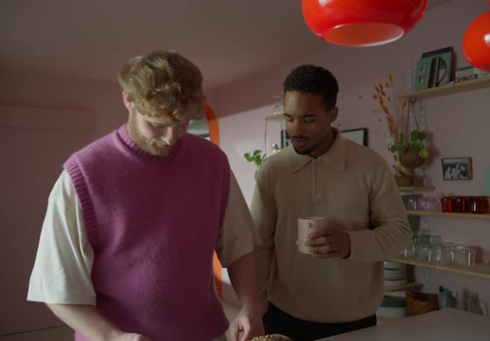 Gay couple prepares dinner and look into each others eyes lovingly in the kitchen
