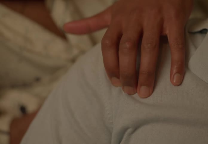Man walks fingers across another mans shoulder before stroking the shoulder