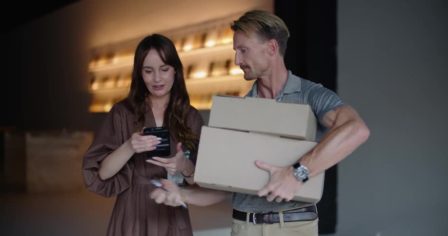 A man delivers two packages to a woman and has her sign a tablet to accept them