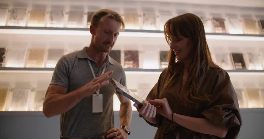 Man unpacks stone sample from box and discusses it with woman