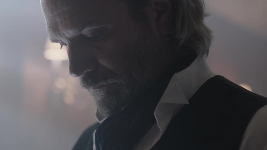 Bearded man wearing a vest looking downwards