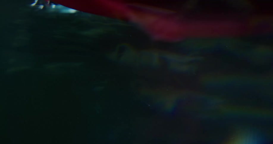 A purple piece of velvet floating in water lights reflect off of it and shadows are created