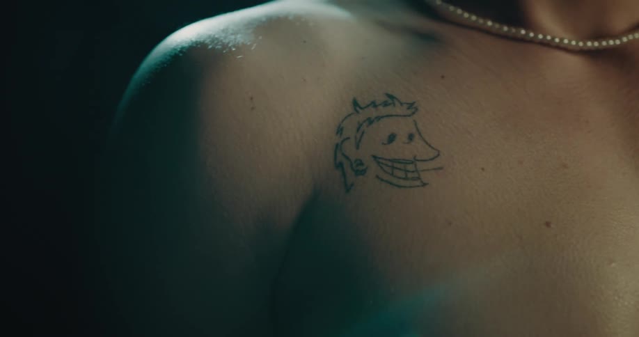 A shirtless man with a tattoo on his shoulder