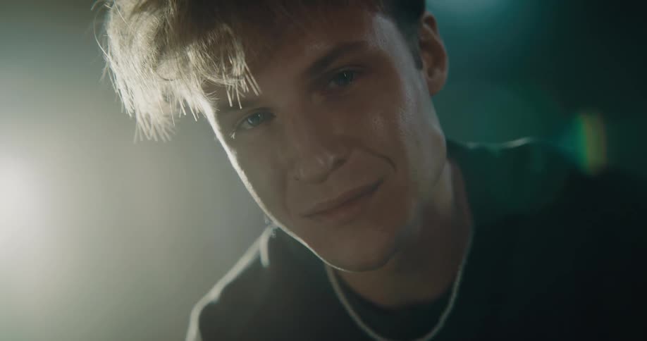 A man tilts his head from side to side and smiles while posing