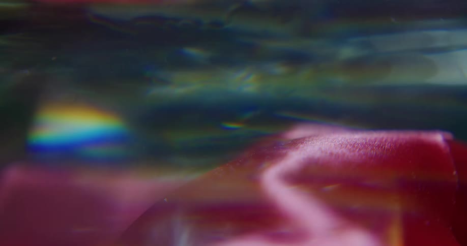 A pink cloth moves and wavers underwater as sunlight shines on the surface