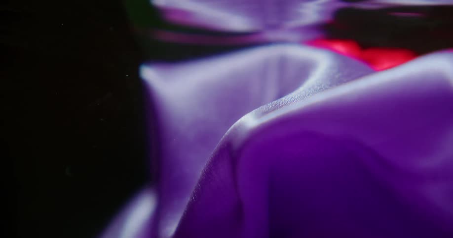 Purple velvet floating in red water creating waves lights and shadow effects