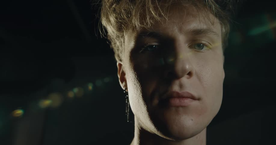 Light shines on the face of a man standing outside at night