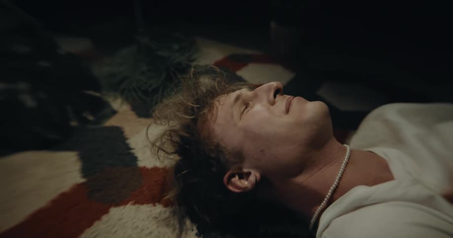A vulnerable looking man lying on an indoor rug