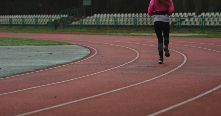 A woman runs around a track in a stadium