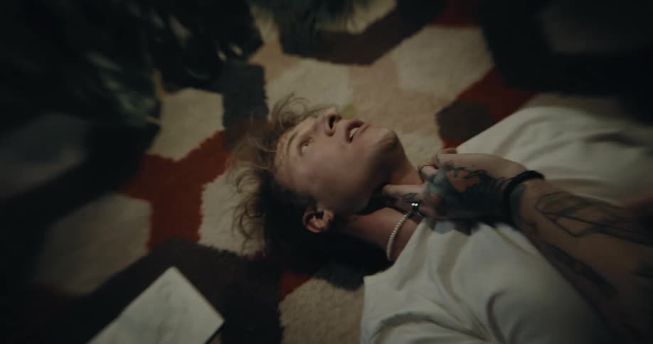 Man checks his pulse while lying on rug in dimly lit room