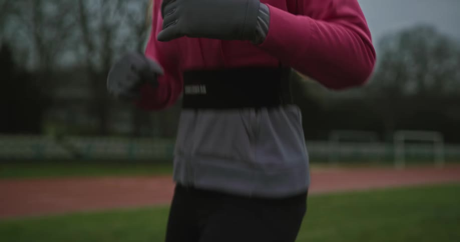 A woman running in place on an outdoor athletic field as part of an exercise routine