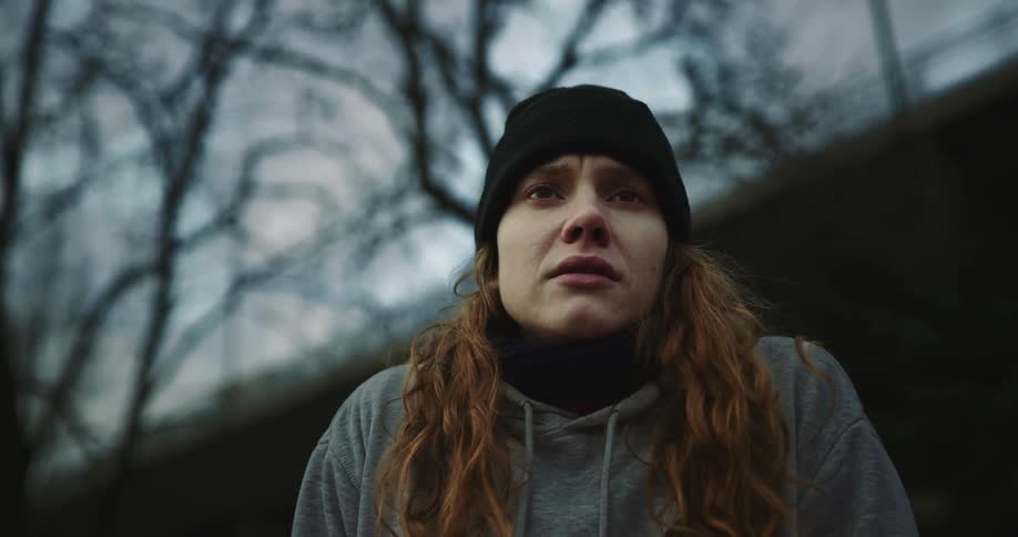 A woman is standing outdoors in the wilderness and looks upset