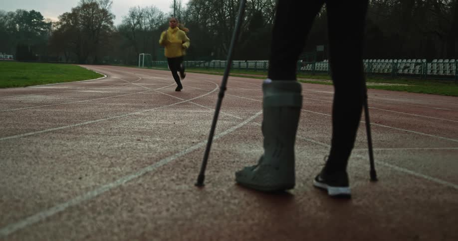 A woman looks on to a woman jogging down the track