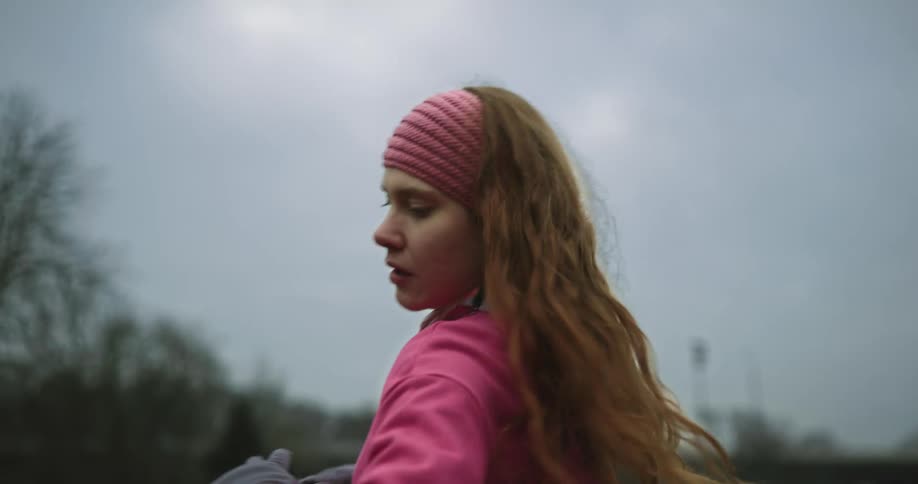 A teenage girl is standing outside in a field exercising and twisting her body