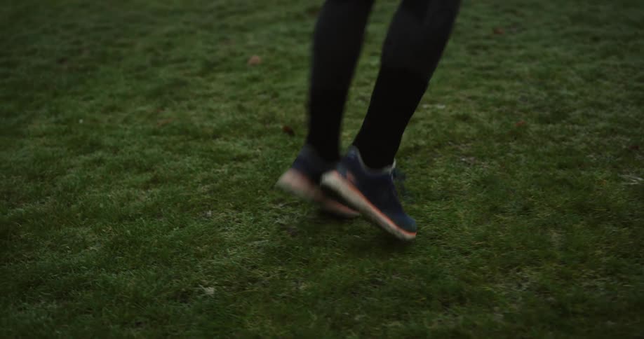 Woman wearing tights runs in place on grass