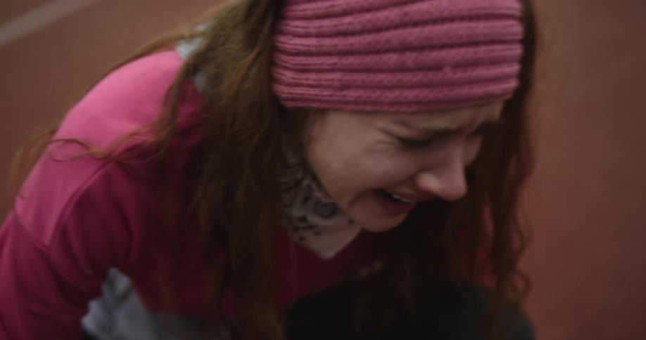 A woman is on the ground on a racetrack in obvious distress crying and holding onto her ankle
