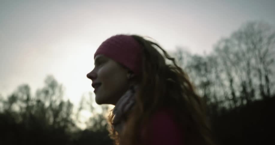A young woman dances outside near some trees and a house