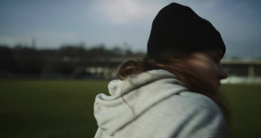Woman limping along running track turns to watch woman running on track in the opposite direction