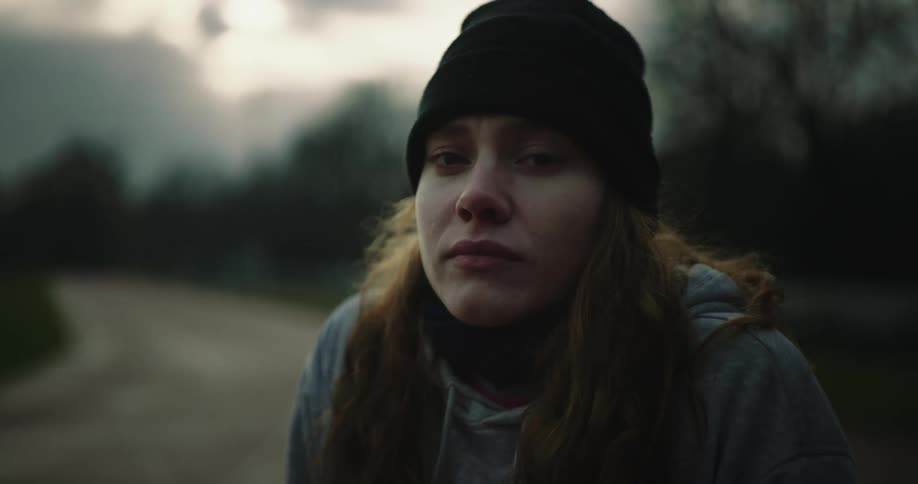 A sad looking woman outside on a chilly cloudy day