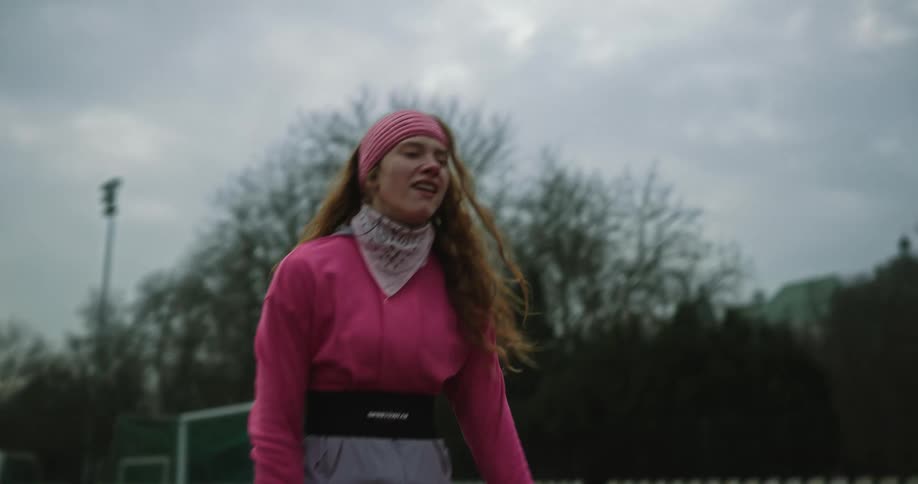 A woman stops to take a breath while running on a track and smiles