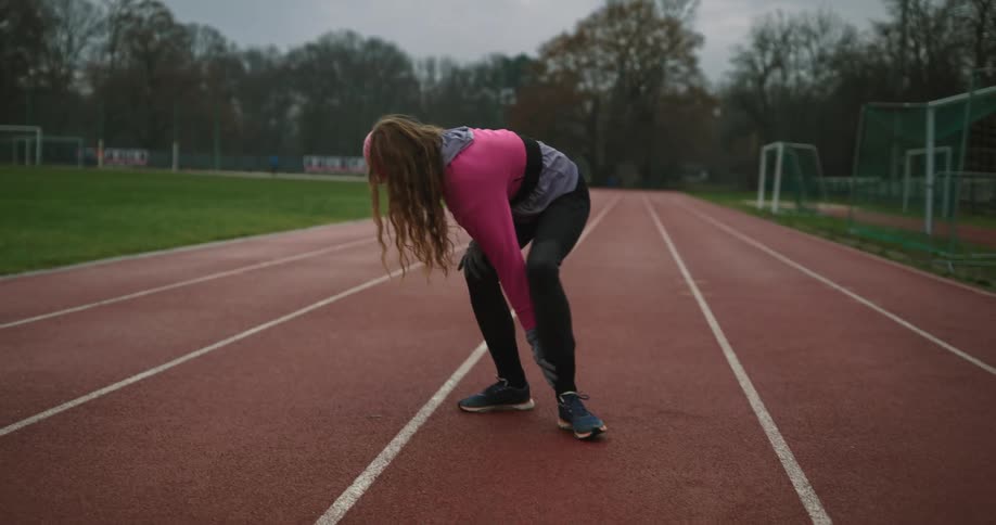 A runner stands up from an injury and limps off track