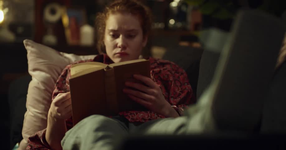 A woman with an injured leg reads a book