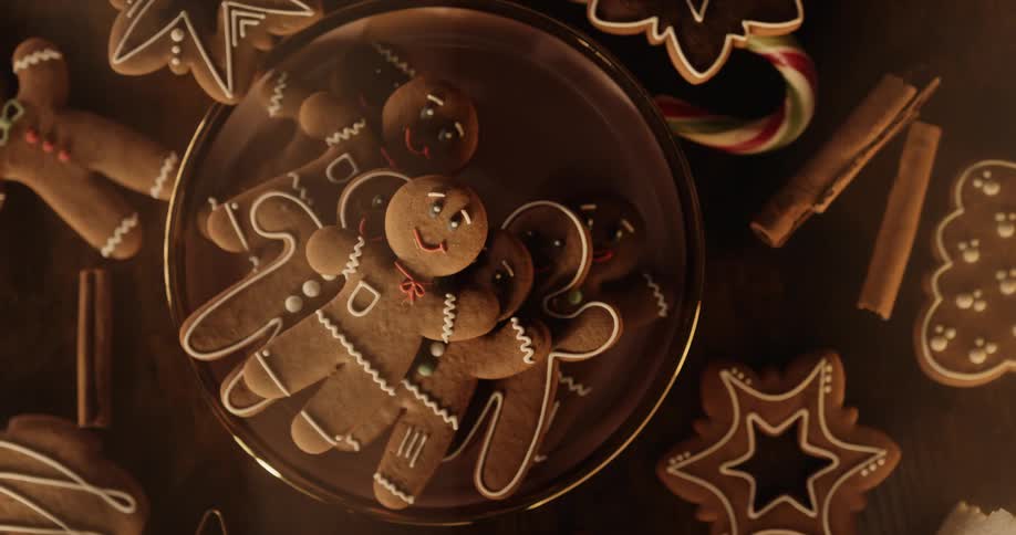 Smiling gingerbread men look up from a plate with cookies on the table with a candy cane