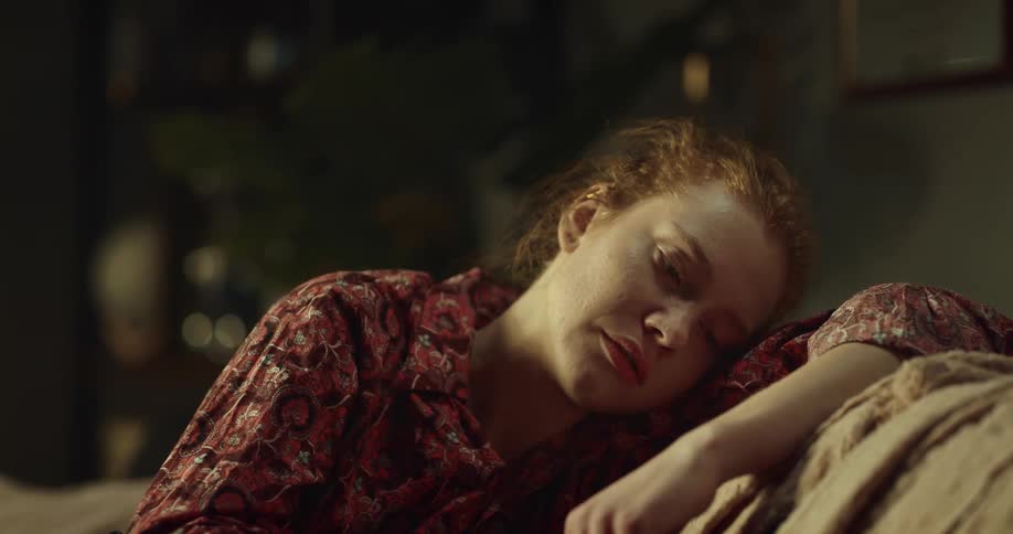 Woman with brown hair and floral blouse falls a sleep on couch in room