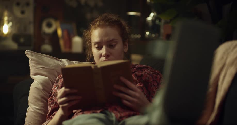 A woman with a broken foot throws her head back while reading