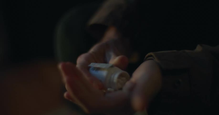 Person puts pill from bottle into their hand