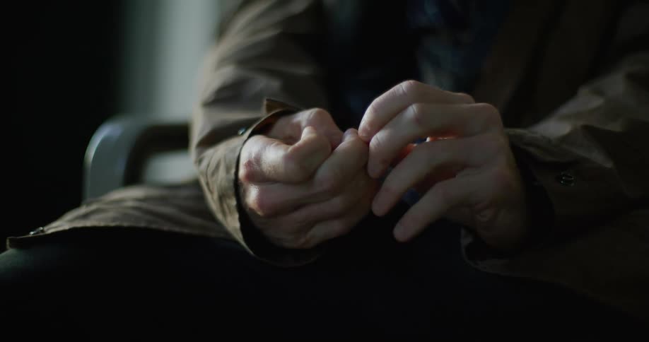 Person sitting on furniture with metal arm examines their hands