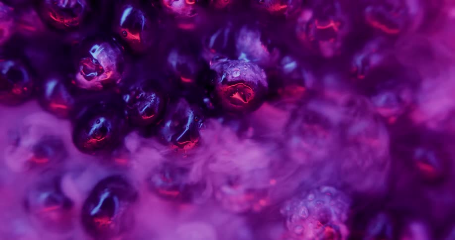 Overhead ecu a pile of cold wet blueberries with pink light condensation and steam coming off