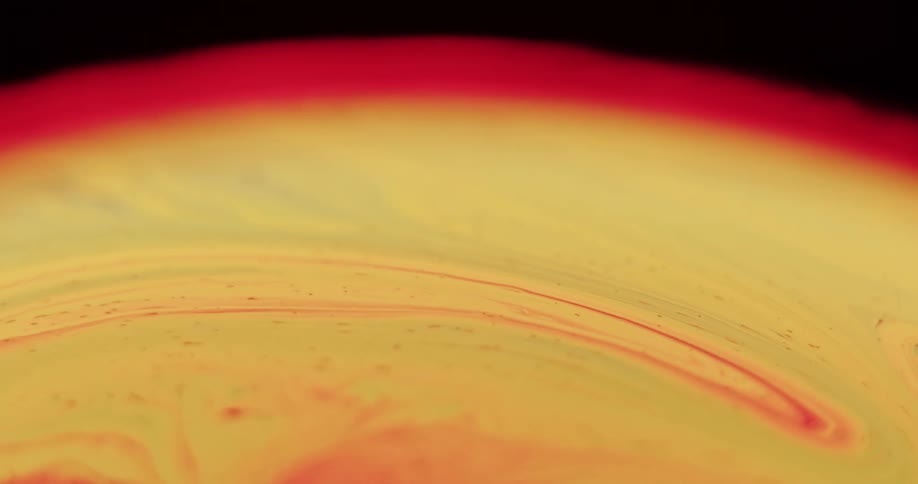Red streaks swirl and blend into the yellow sphere that is glowing red around the edge