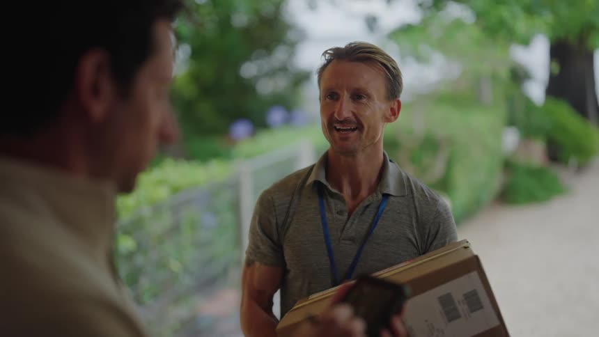 A man opens his front door as a delivery man is holding his package and he signs the signature pad and the man hands him his box